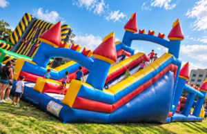 Full Obstacle Course with children climbing and sliding through a colorful inflatable course at an outdoor event.