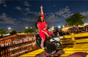 Woman enjoying a Mechanical Bull ride at a lively nighttime outdoor event.