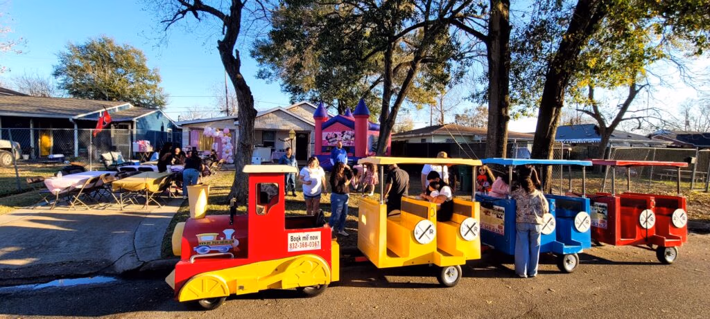 Colorful trackless train parked at an outdoor festival with inflatable attractions