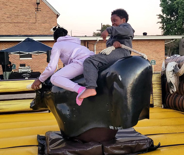 Children riding a mechanical bull at an outdoor event